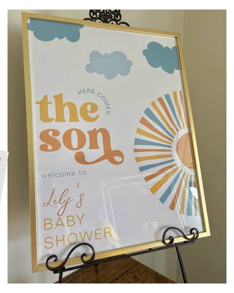 Welcome sign for a 'Here Comes the Son' baby shower with retro font and a sun graphic in a gold frame.