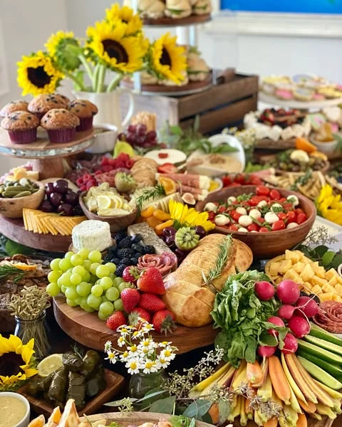 A of a charcuterie board section on a grazing table, featuring cheeses, grapes, strawberries, bread, and a caprese salad.