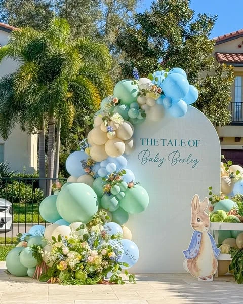 Modern arched backdrop for a Peter Rabbit baby shower with a pastel balloon garland.