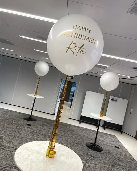 of a personalized 'Happy Retirement' balloon with custom gold lettering and a tassel.