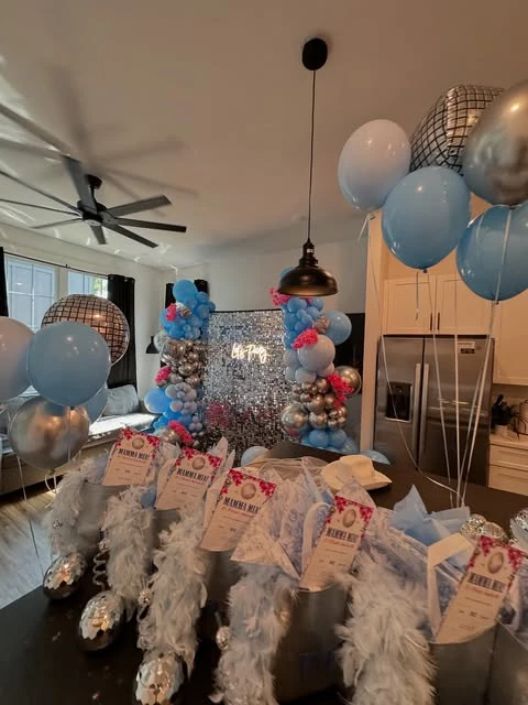 A of Mamma Mia party favors, including light blue feather boas and disco ball cups.