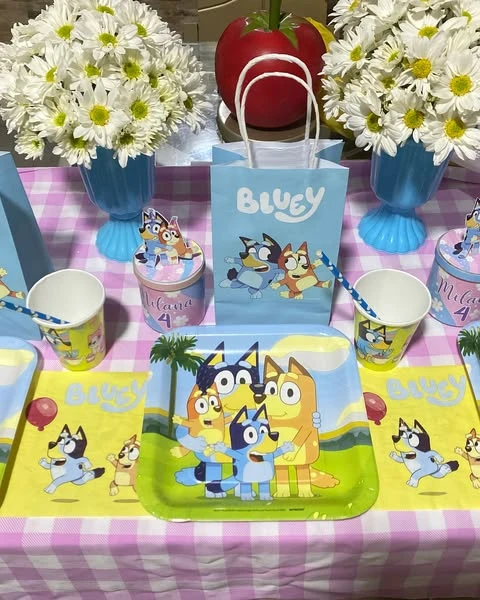 of a Bluey-themed party place setting with a paper plate, cup, and favor bag.