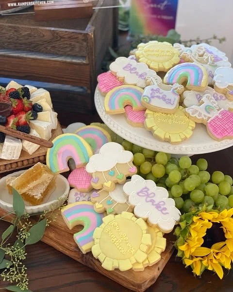 Custom sugar cookies on a dessert platter shaped like suns and clouds for a 'You Are My Sunshine' baby shower.