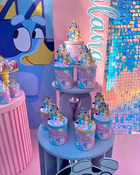Bluey-themed dessert display with treat boxes and character cutouts against a pastel backdrop.