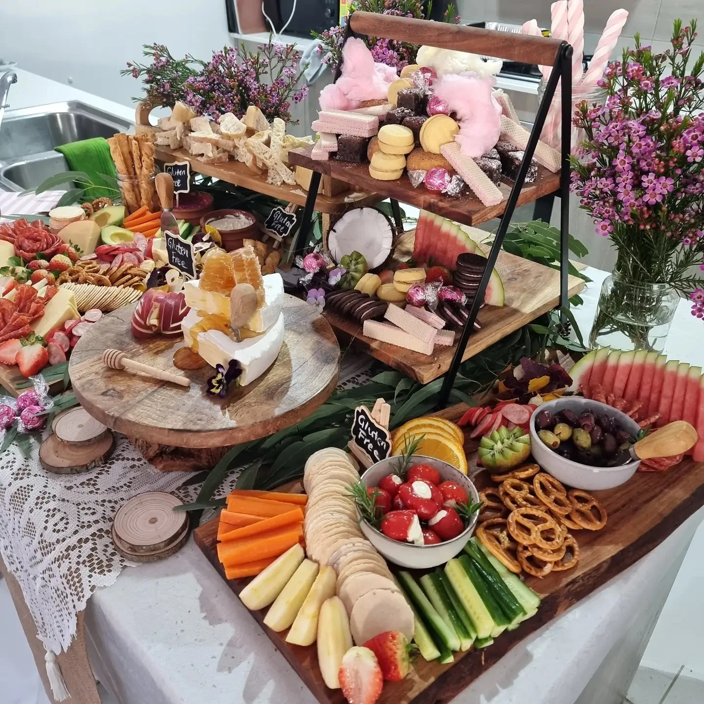 An abundant baby shower grazing table featuring a mix of sweet and savory foods on wooden boards and a tiered stand.