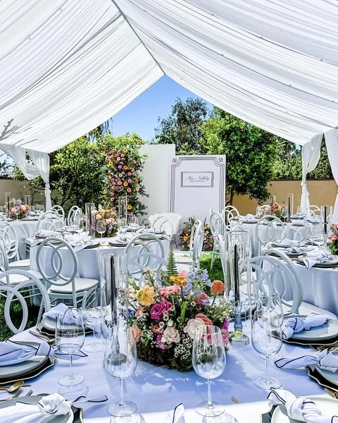Outdoor tented spring bridal shower with long tables and colorful floral centerpieces.