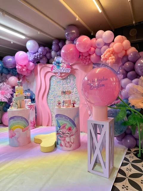 Stitch and Angel themed birthday party dessert table with a large pink and purple balloon arch.
