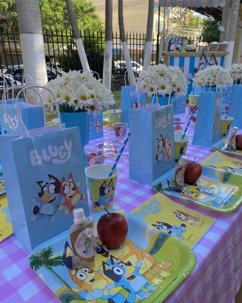 Bluey-themed party favor bags and table decorations, including fresh flowers.