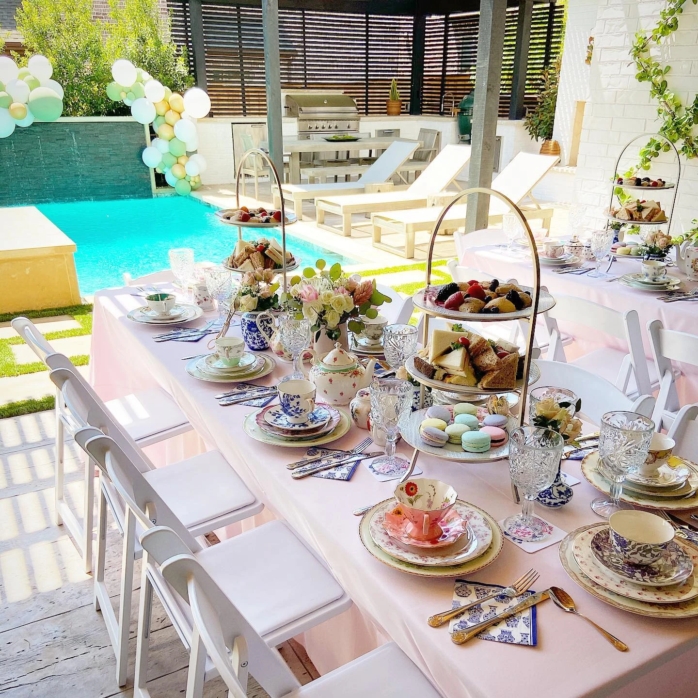 Elegant tea party bridal shower table set with mismatched vintage floral china and tiered food stands.
