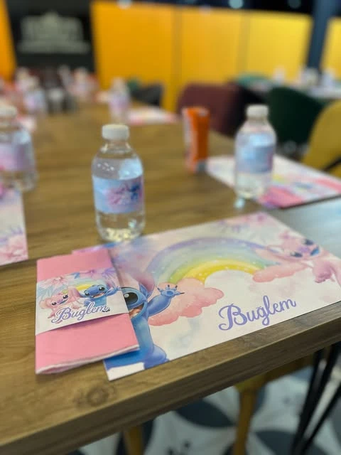of a party table setting with a custom Stitch and Angel paper placemat, napkin holder, and water bottle.