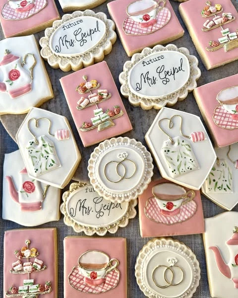 An assortment of pink and white tea party bridal shower cookies with teapot and teacup shapes.