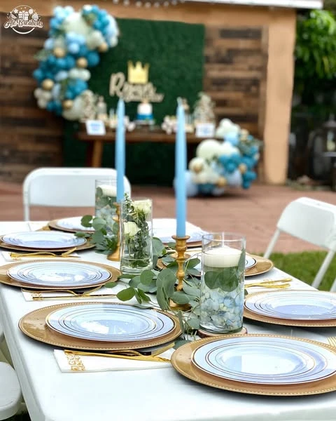 Baby shower table centerpiece with floating candles, submerged blue hydrangeas, and a eucalyptus runner.