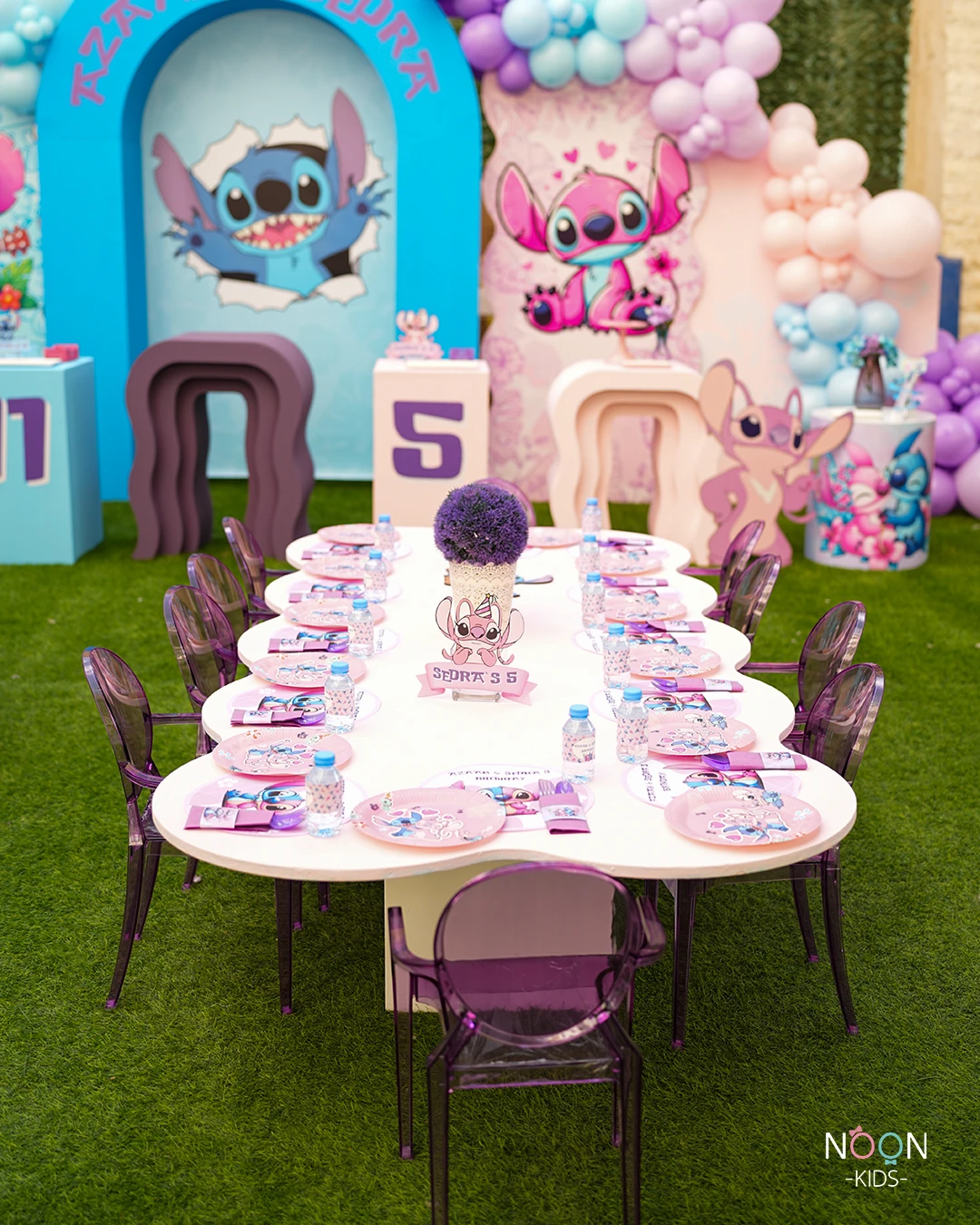 Pastel Stitch and Angel birthday party with a long, cloud-shaped kids' table and large character backdrops.