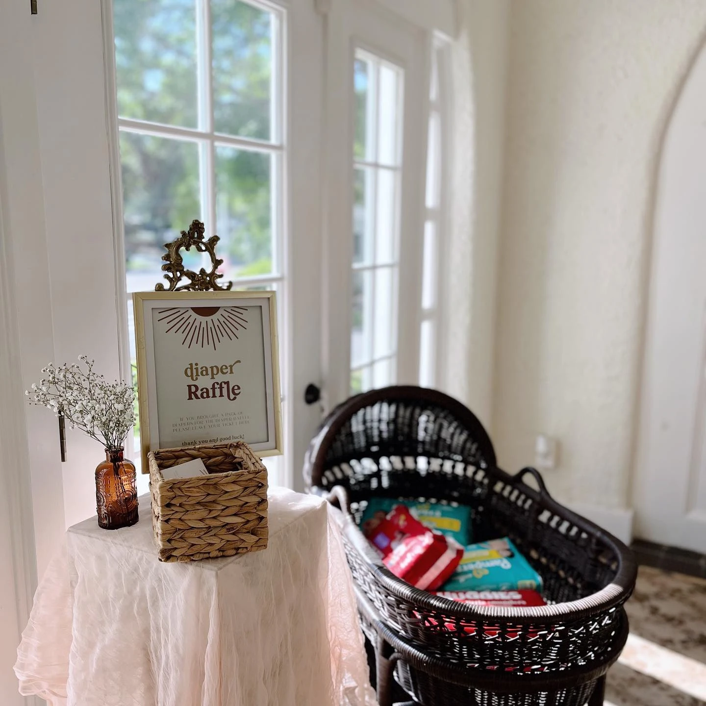 A diaper raffle station at a 'you are my sunshine' baby shower with a sign and bassinet.