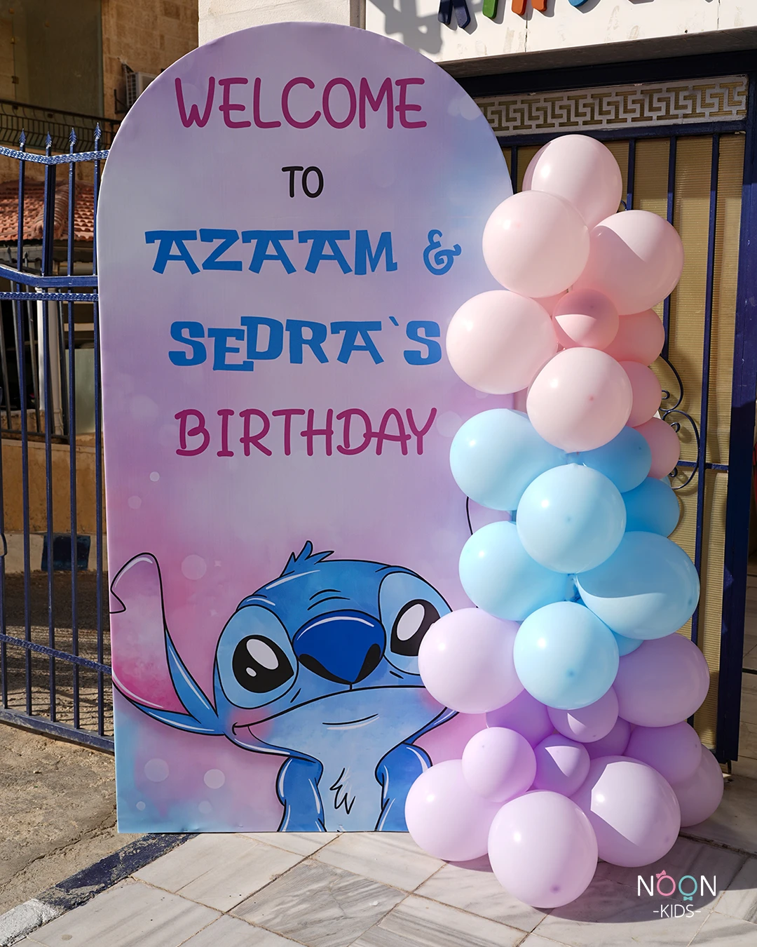 A large, arched welcome sign for a Stitch birthday party, decorated with pastel balloons.