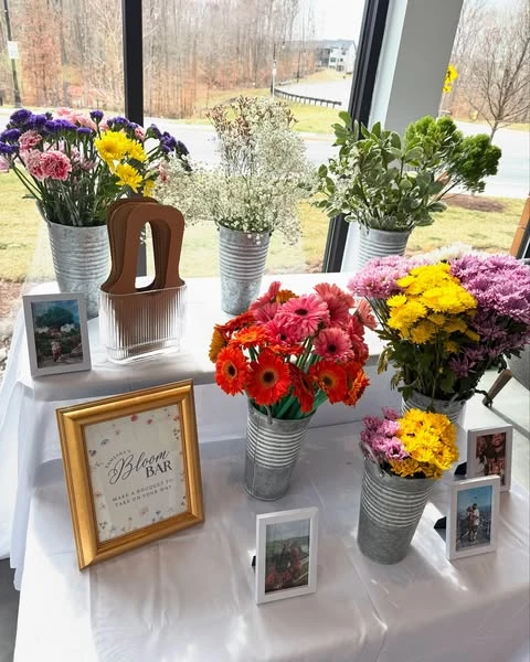 A 'Bloom Bar' station at a bridal shower with buckets of fresh flowers for guests to create their own bouquets.