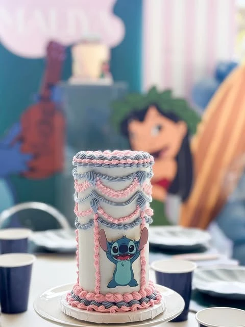 Tall Stitch birthday cake with pink and blue vintage-style piping.