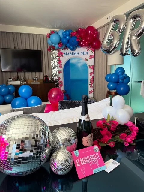 A Mamma Mia themed bachelorette party setup with large disco balls in the foreground.
