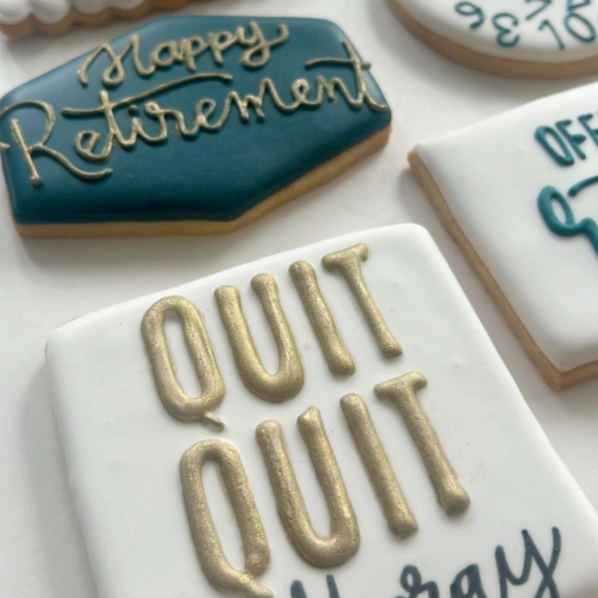 Retirement-themed cookies with gold and teal icing, one saying 'QUIT QUIT QUIT'.
