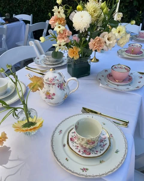 A of a tea party bridal shower place setting with a floral teacup and a low flower centerpiece.