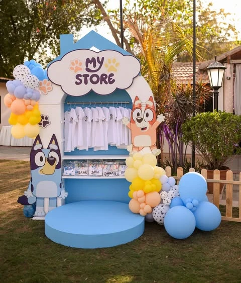 Bluey and Bingo character cutouts next to a house-shaped party backdrop.