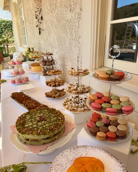 A dessert table for a tea party bridal shower filled with macarons, cookies, and cakes on tiered stands.