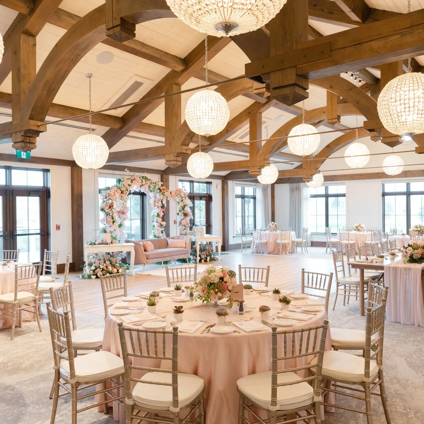 Bridal shower venue with round tables dressed in pink tablecloths and gold chairs, showing a cohesive floral theme.