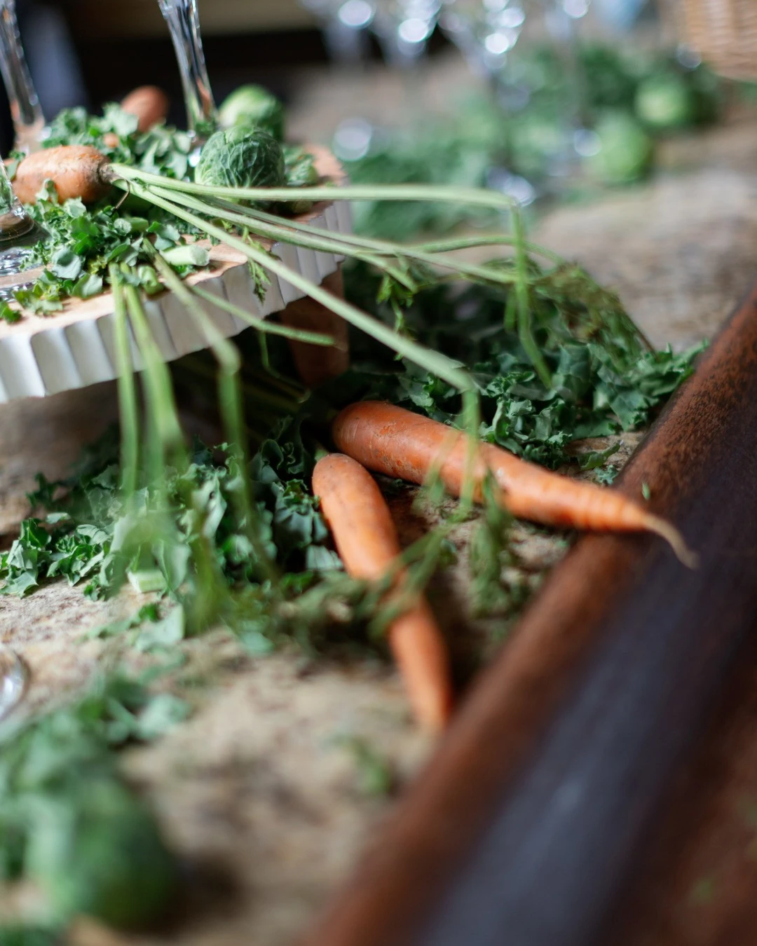 A of fresh carrots and kale used as table scatter decor for a garden-themed party.