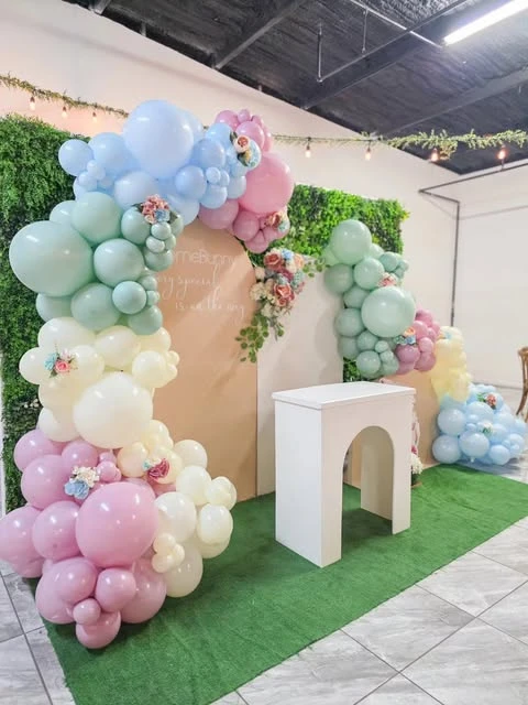 A pastel balloon arch with wildflower accents for a baby shower photo backdrop.