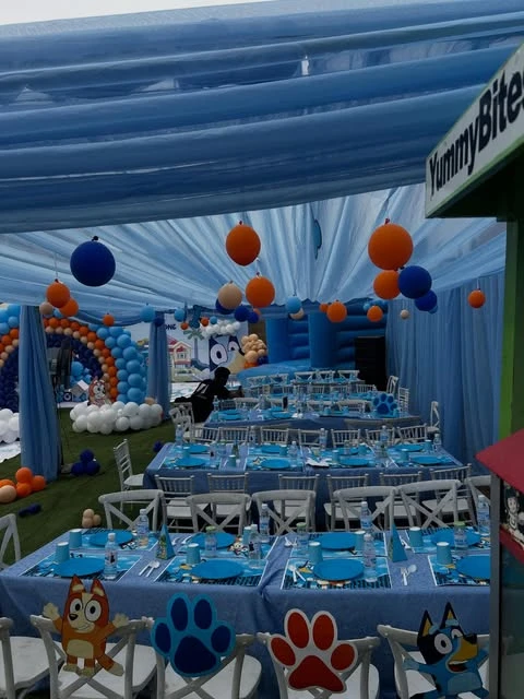 Bluey-themed birthday party tables with Bluey and Bingo character cutouts on the backs of chairs.