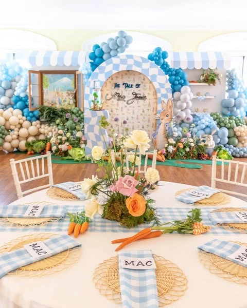 Peter Rabbit baby shower table setting with blue checkered napkins and rattan placemats.