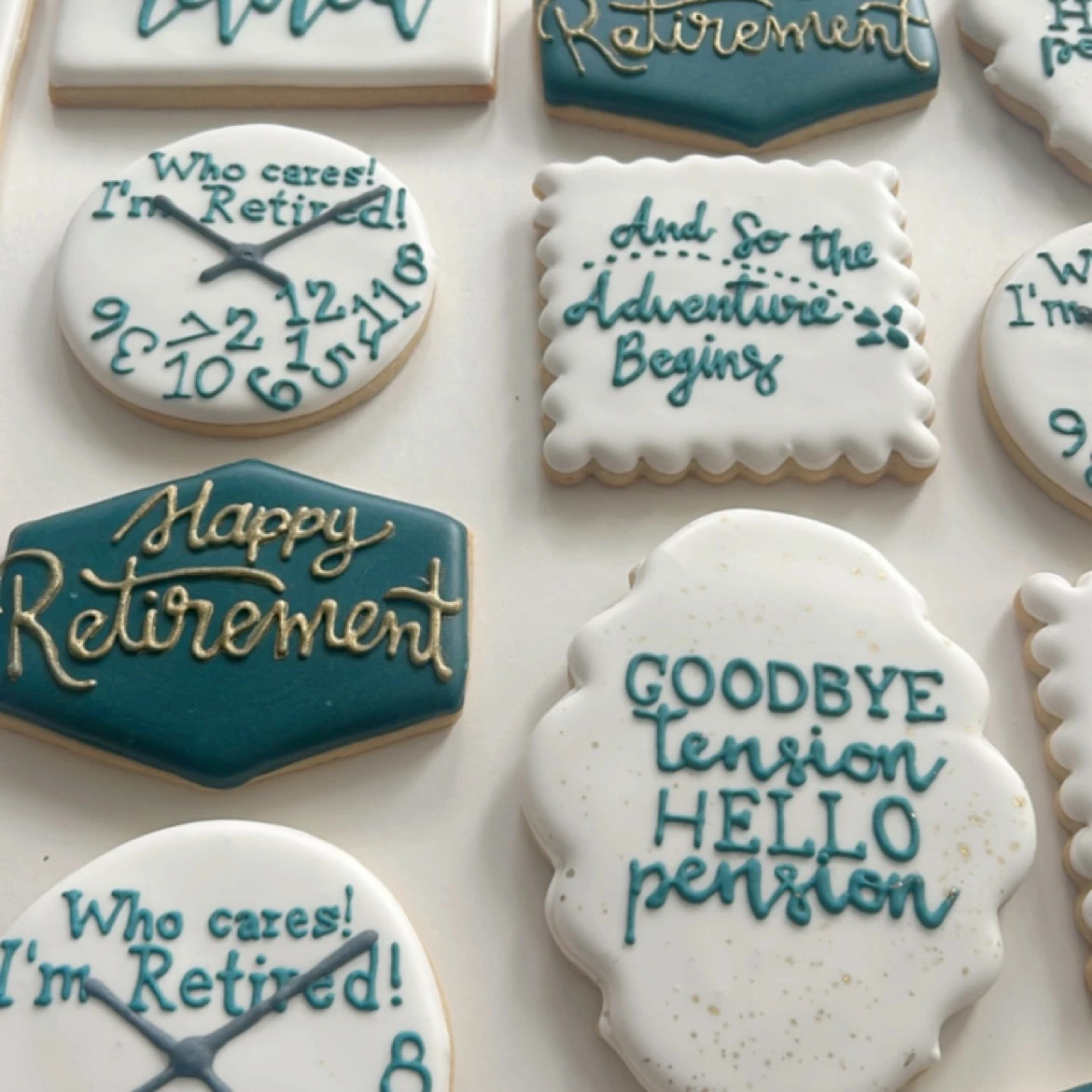 Assortment of decorated retirement party cookies in teal, gold, and white.