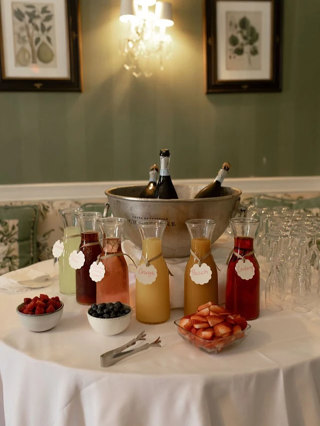 Mimosa bar setup with juices, champagne, and fruit for a bridal shower.