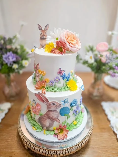 A two-tiered wildflower baby shower cake decorated with edible flowers and butterflies.