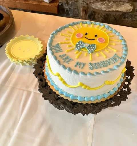 'You are my sunshine' themed baby shower cake with a smiling sun topper.