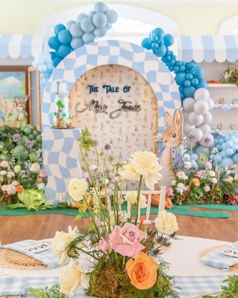 Garden-style floral centerpiece with roses and fresh carrots for a Peter Rabbit baby shower.