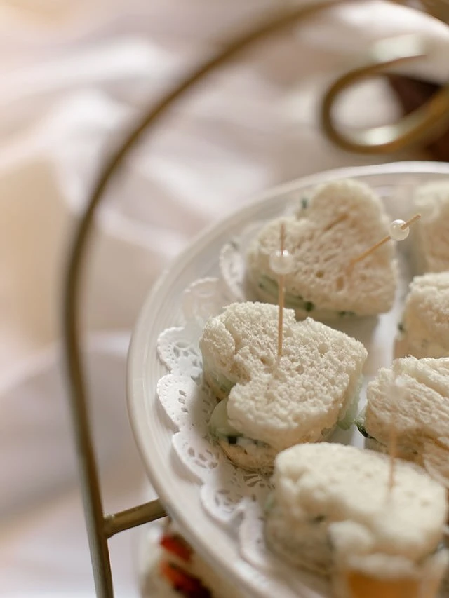 Heart-shaped finger sandwiches on a tiered tray for a tea party.