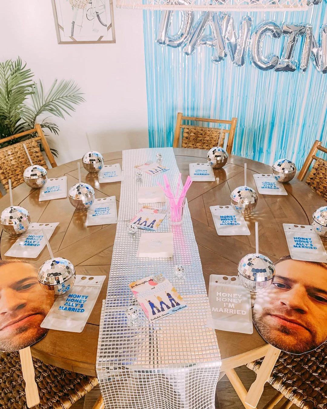 Mamma Mia themed bachelorette party table setting with disco ball cups and 'Honey Honey I'm Married' drink pouches.
