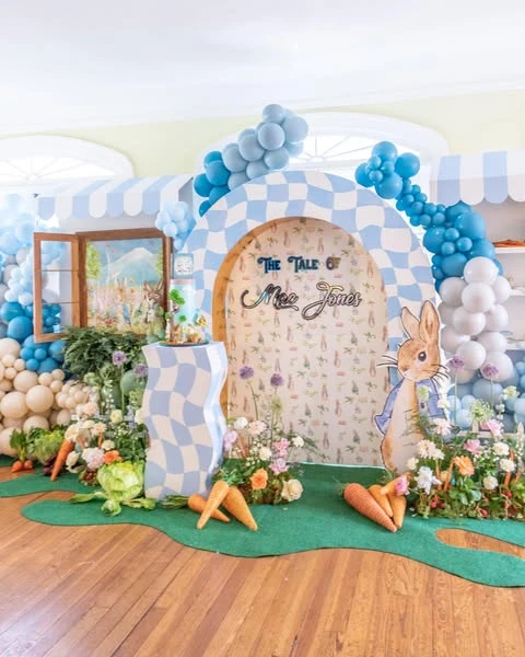 A large organic balloon arch in blue, tan, and white for a Peter Rabbit baby shower.