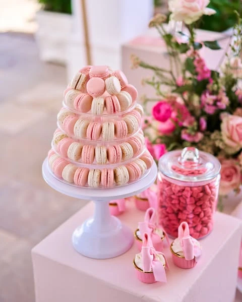 Pink and cream macaron tower on a white stand for a spring bridal shower dessert table.