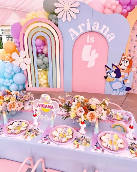 A Bluey and Bingo themed birthday party with a pastel rainbow backdrop and matching table setting.