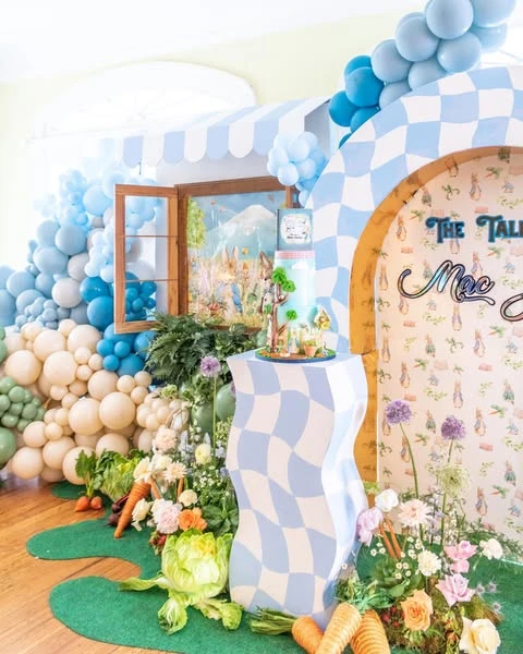 A wavy, checkered cake stand placed within a Peter Rabbit garden market backdrop.