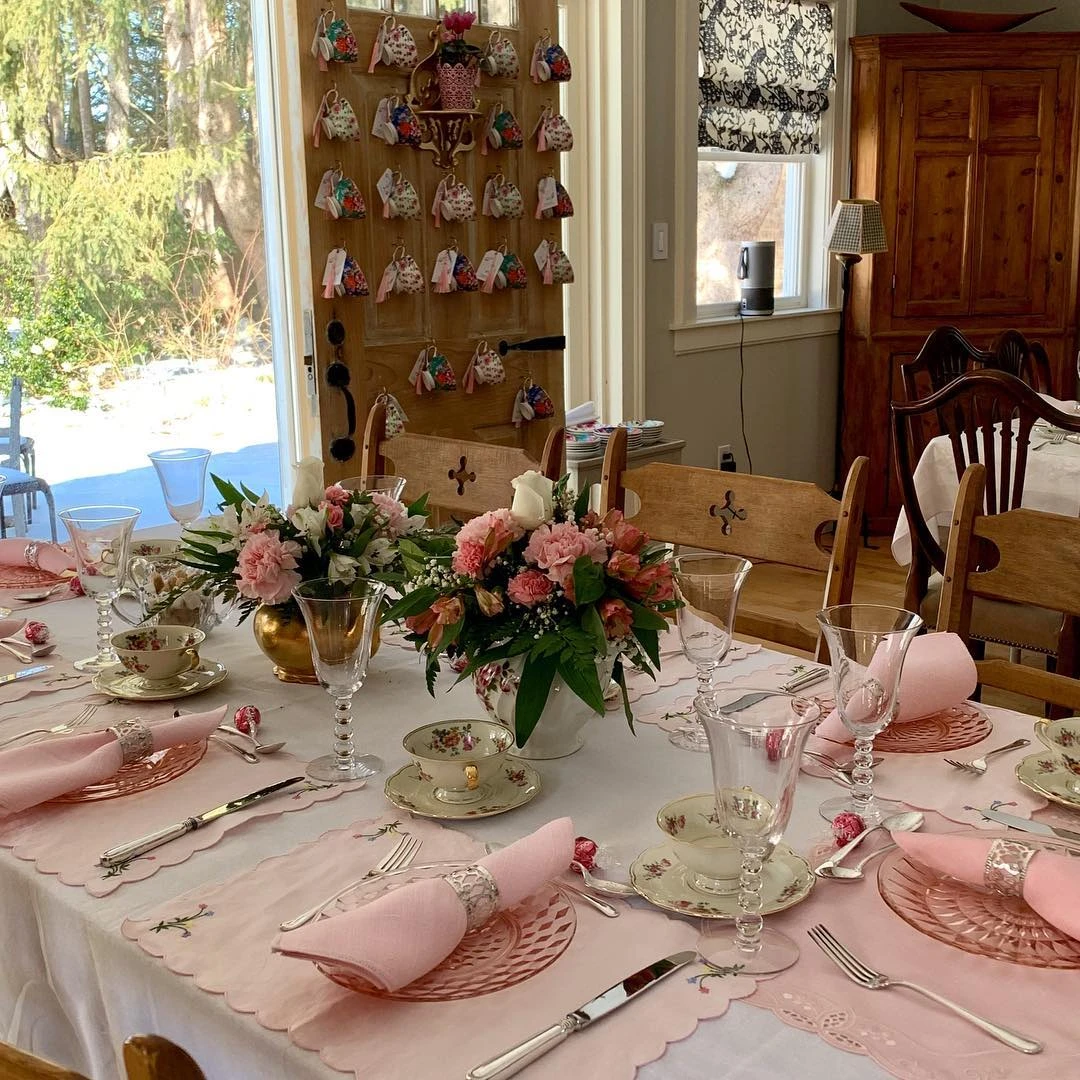 Elegant tea party bridal shower tablescape with pink linens and a teacup display wall.