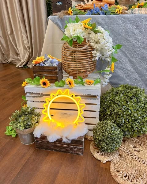 Yellow neon sun sign decor for a Here Comes the Sun baby shower, placed in a wooden crate.