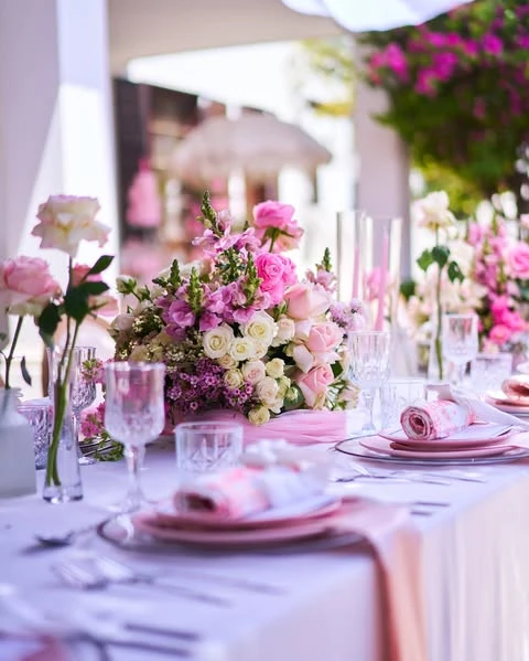 of a pink and white place setting with a floral centerpiece for a spring bridal shower.