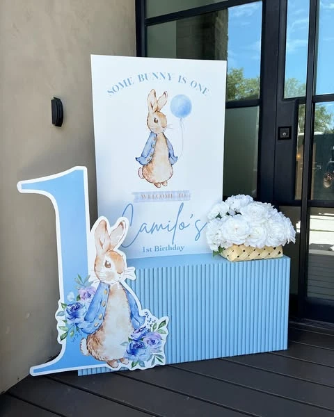 A Peter Rabbit themed welcome sign on a blue plinth with a character cutout, styled for a baby shower entrance.