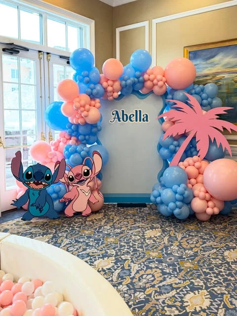 A Stitch and Angel themed birthday party photo backdrop with a pink and blue balloon arch.