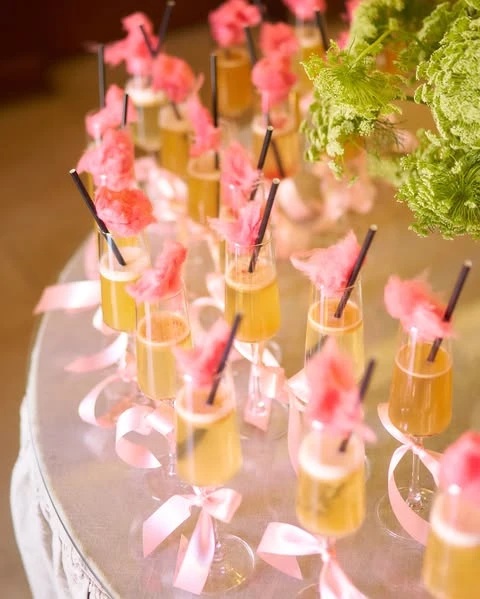 Champagne flutes garnished with pink cotton candy for a whimsical bridal shower cocktail.