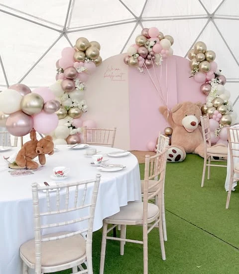Guest tables at a 'We can bearly wait' baby shower with a large backdrop in the background.