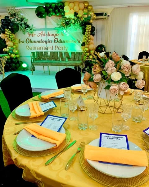 Elegant retirement party decor featuring a gold, black, and green balloon arch over a formal dining table.
